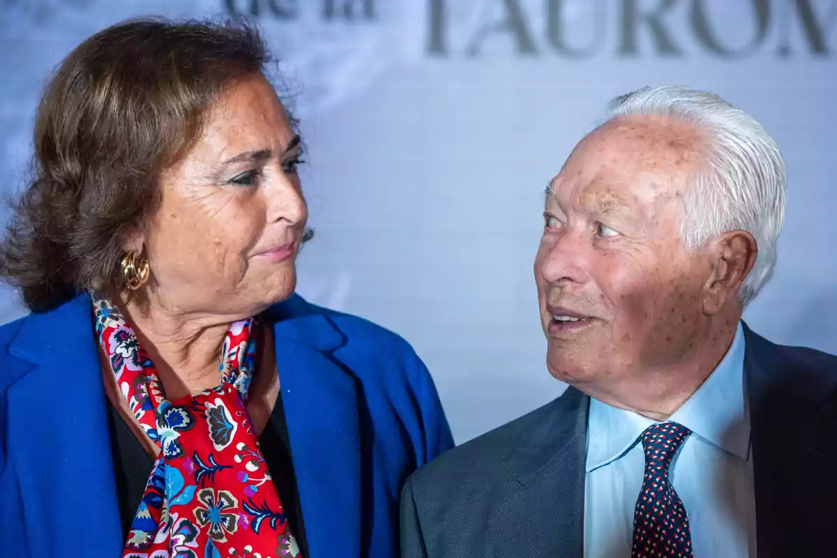 Dos personas mayores mirándose con expresiones amables y vestimenta formal. Dos personas mayores mirándose con expresiones amables y vestimenta formal.