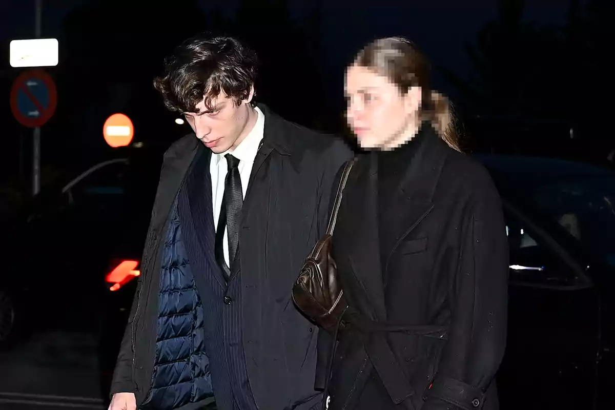 Un hombre y una mujer caminando juntos por la noche, ambos vestidos con abrigos oscuros. Un hombre y una mujer caminando juntos por la noche, ambos vestidos con abrigos oscuros.