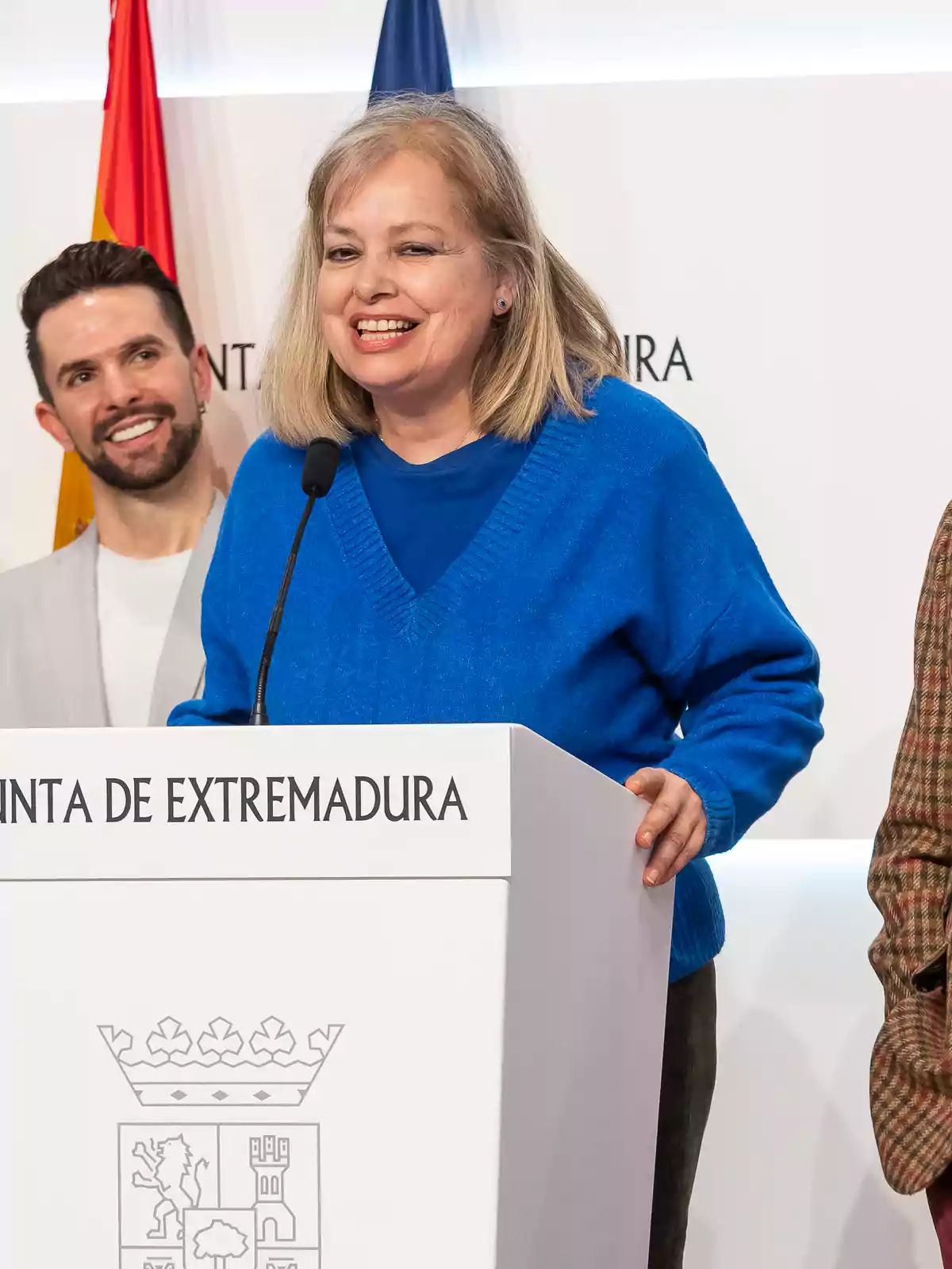 Una mujer sonriente habla en un podio con el texto Una mujer sonriente habla en un podio con el texto