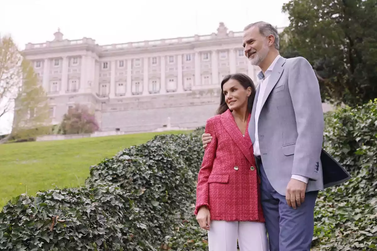 Una pareja posando frente a un edificio histórico en un jardín. Una pareja posando frente a un edificio histórico en un jardín.