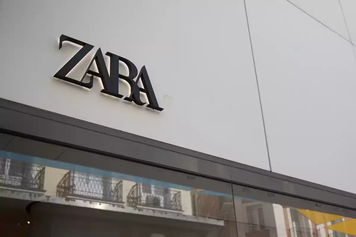 Fachada de una tienda con el letrero de Zara en letras negras sobre una pared blanca Fachada de una tienda con el letrero de Zara en letras negras sobre una pared blanca