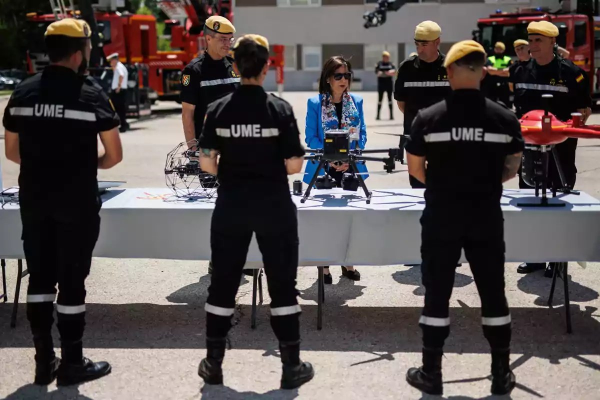 Un grupo de personas de la UME observa drones en una mesa al aire libre durante una demostración.