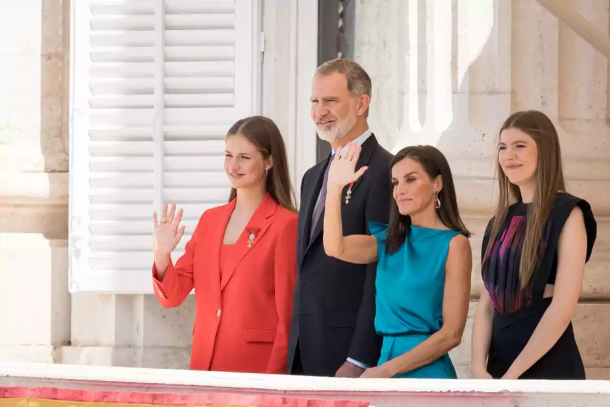 Una familia real saludando desde un balcón en un evento oficial.