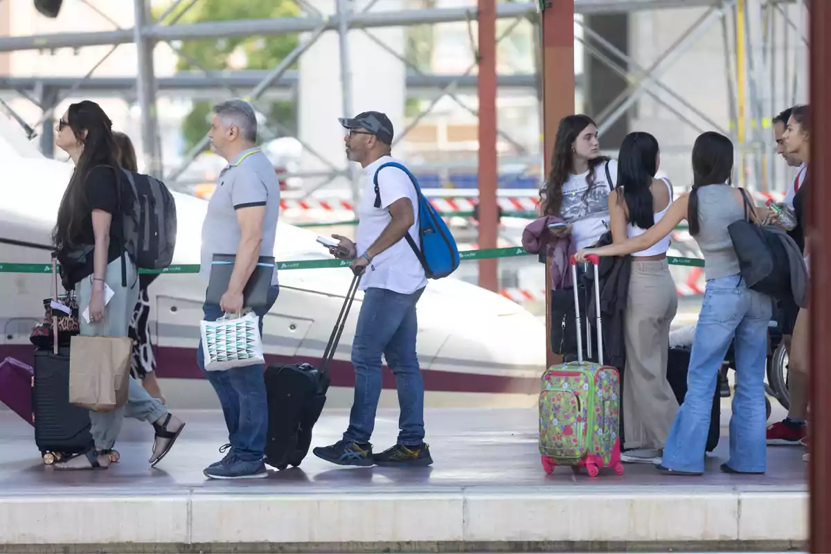 Personas esperando en una estación de tren con equipaje.