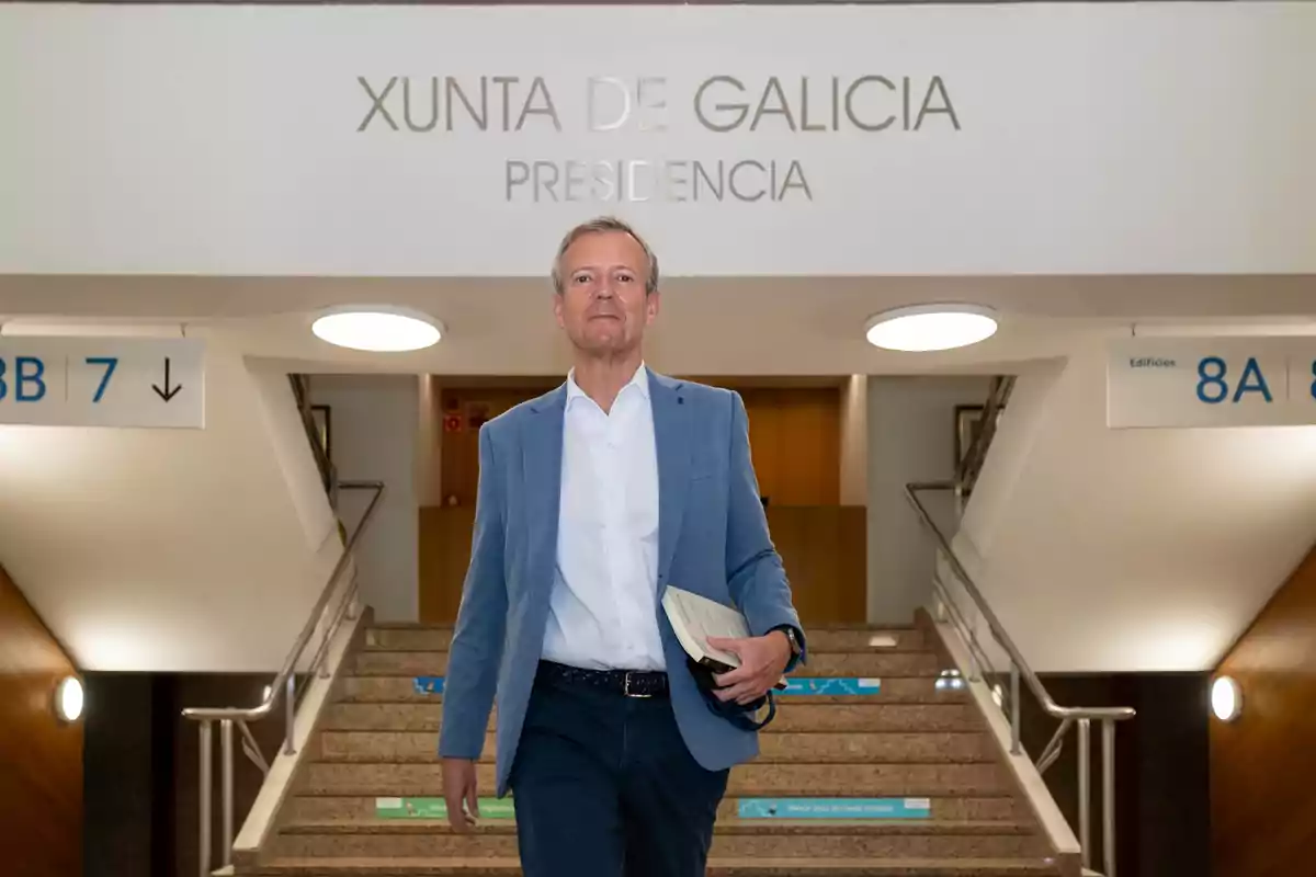 Hombre con chaqueta azul y camisa blanca bajando unas escaleras en un edificio oficial de la Xunta de Galicia Hombre con chaqueta azul y camisa blanca bajando unas escaleras en un edificio oficial de la Xunta de Galicia