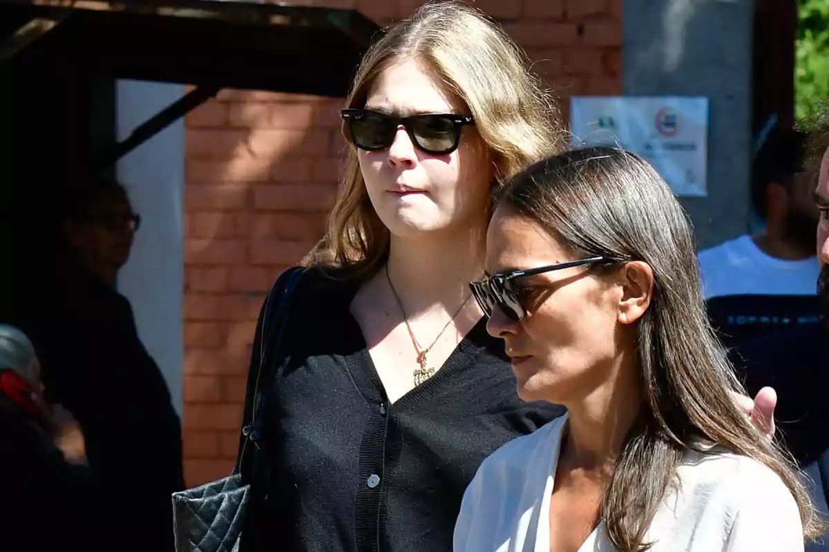 Dos personas con gafas de sol caminan juntas en un entorno urbano. Dos personas con gafas de sol caminan juntas en un entorno urbano.