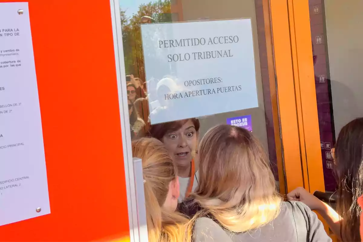 Varias personas se encuentran frente a una puerta con un cartel que dice 