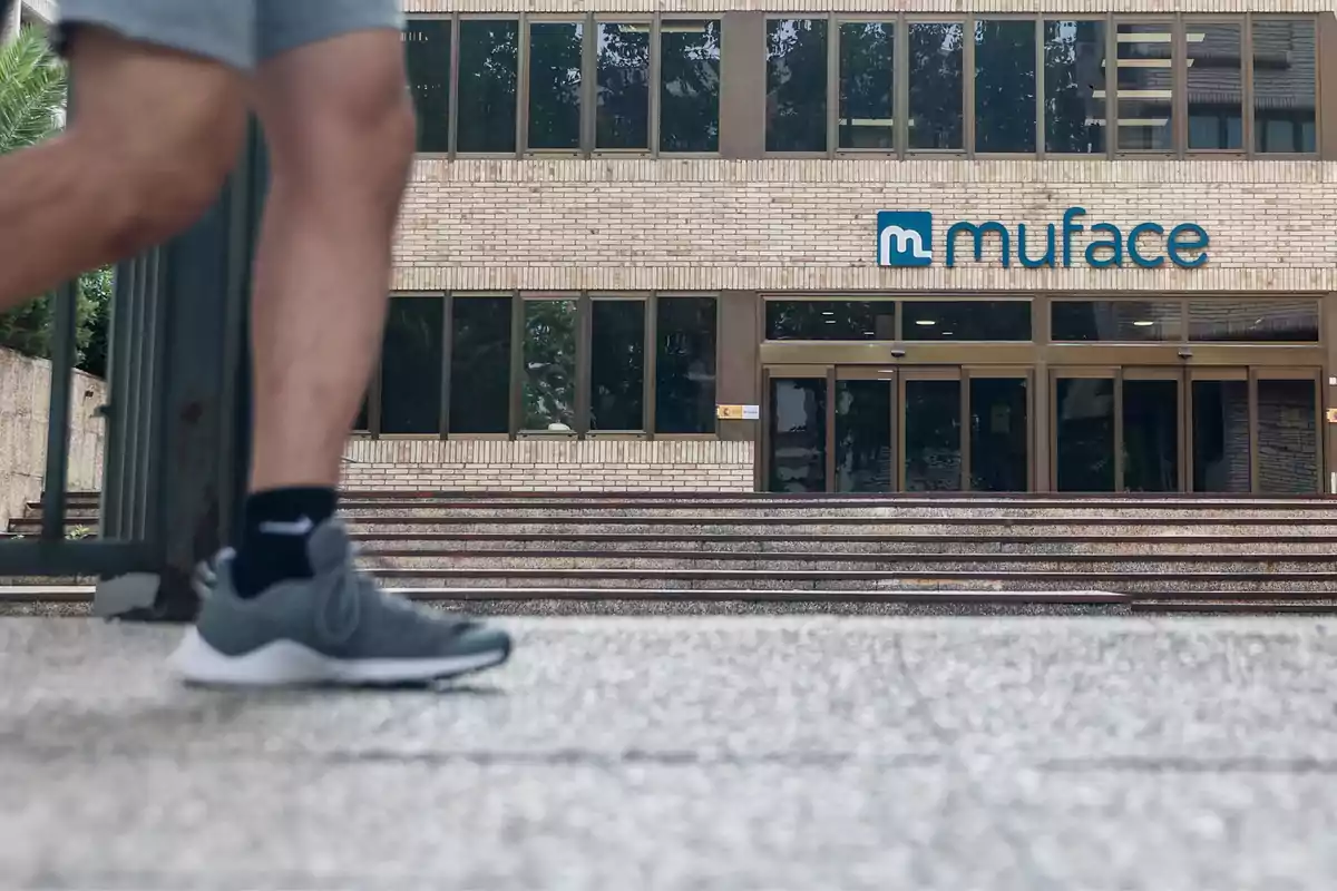 Una persona caminando frente a un edificio con el logo de Muface en la fachada.