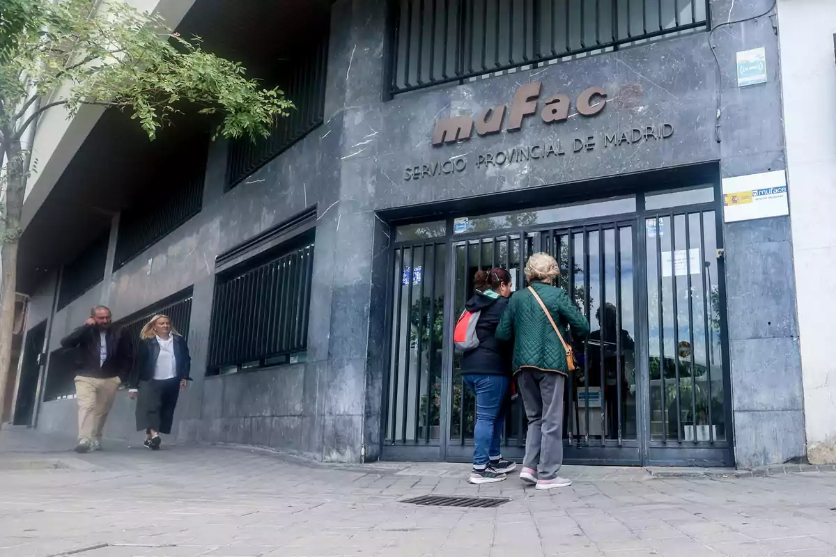 Personas frente a la entrada de un edificio con el letrero 