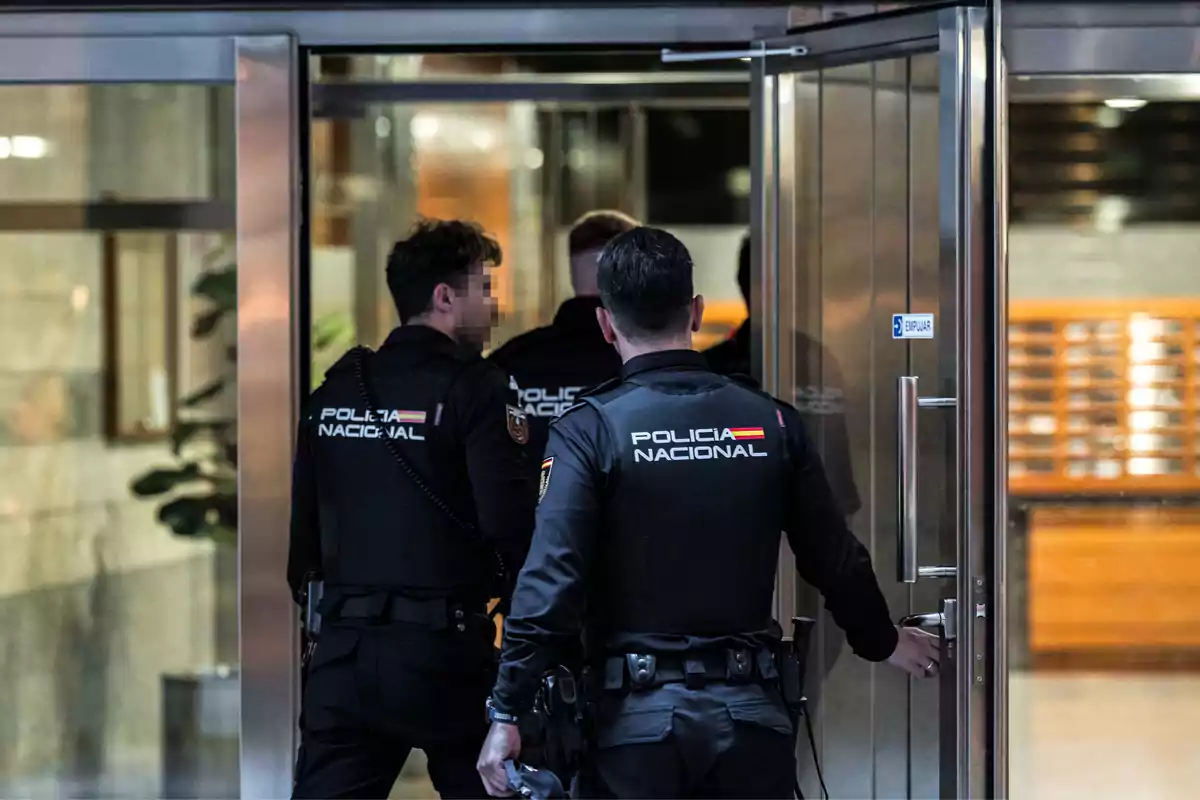 Policías nacionales entrando a un edificio a través de una puerta de cristal.