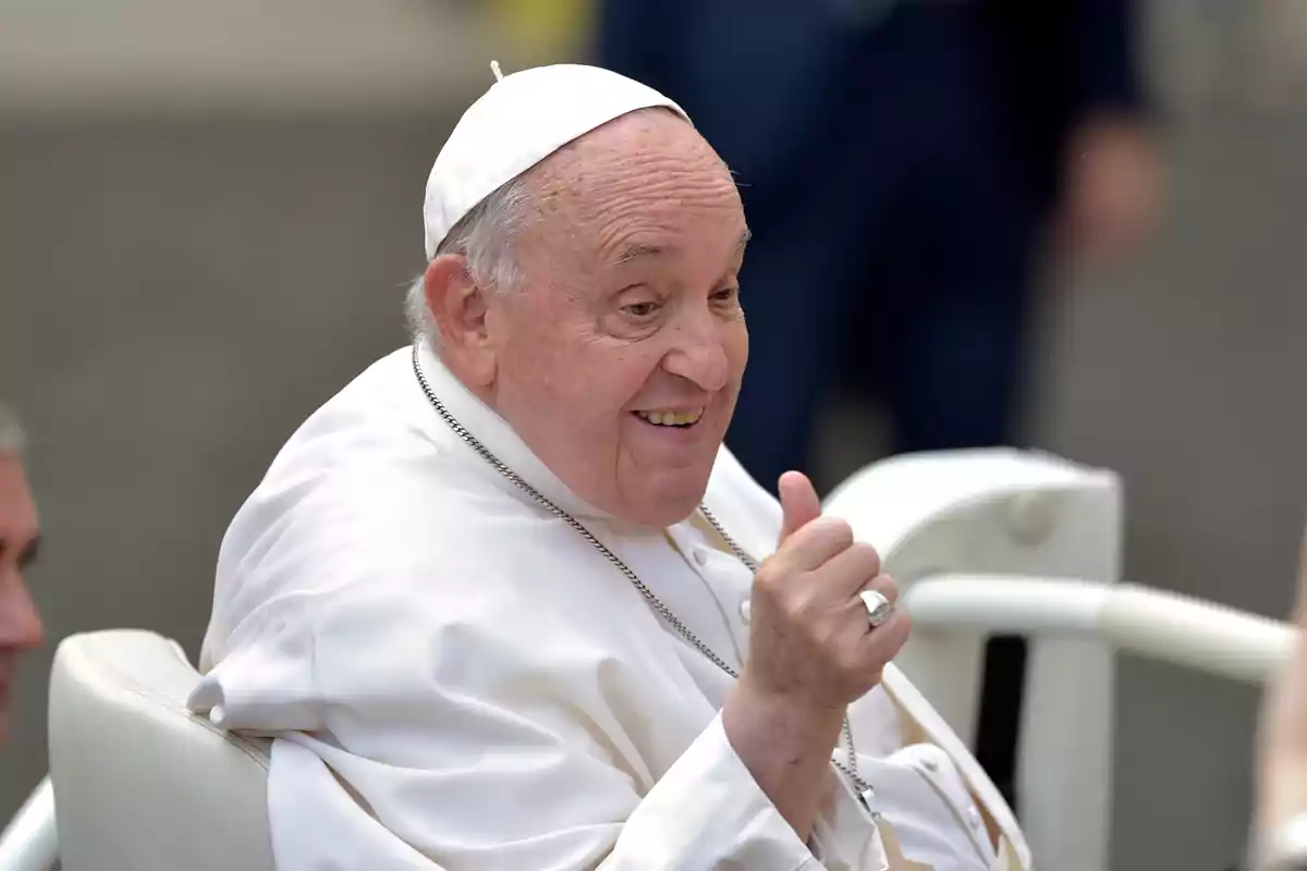 Un hombre mayor vestido con atuendo religioso blanco sonríe y levanta el pulgar.