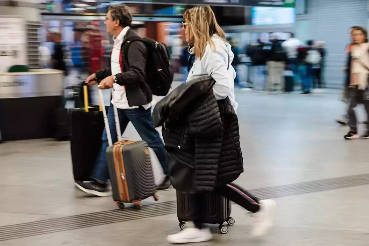 Personas caminando en un aeropuerto con maletas y abrigos.