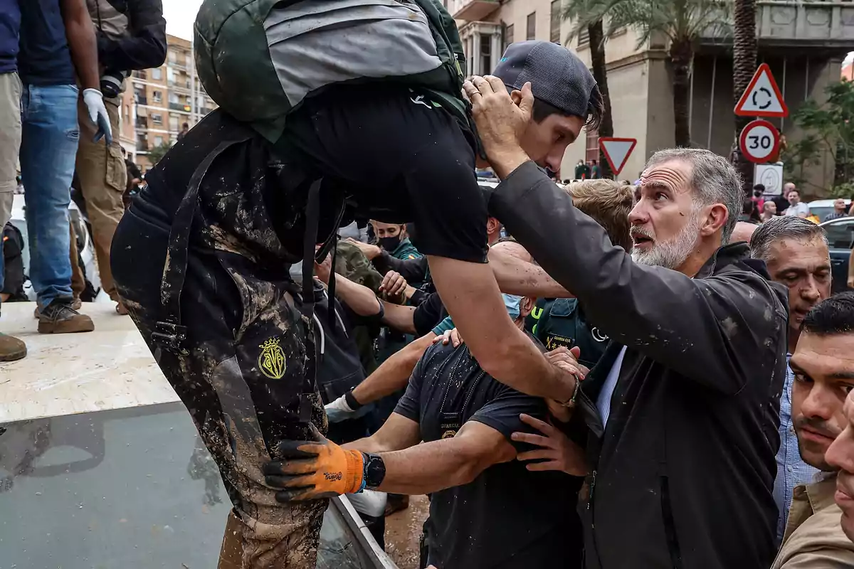 Un grupo de personas ayuda a un hombre a bajar de un vehículo en una calle concurrida.