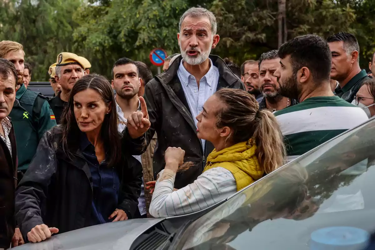 Un grupo de personas conversando al aire libre, algunas de ellas parecen estar en una discusión o intercambio serio.