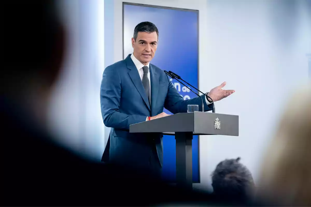 Un hombre en traje azul habla en un podio durante una conferencia de prensa.