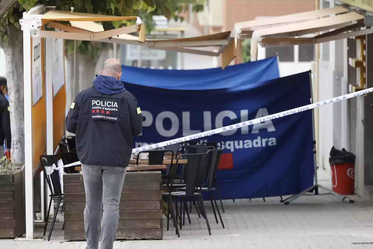 Un agente de policía investiga una escena acordonada en una terraza al aire libre.