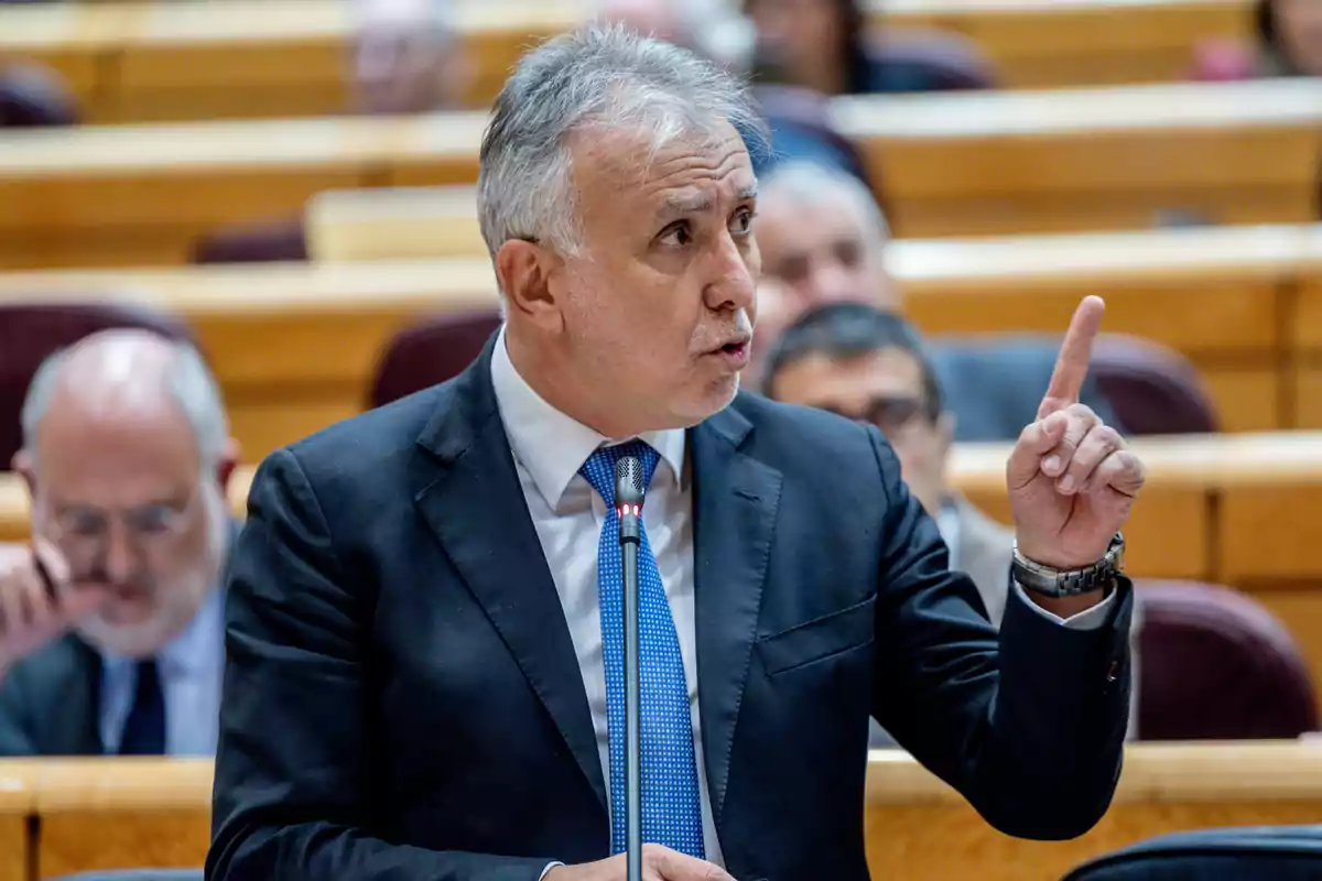 Un hombre en traje hablando en un podio en un entorno formal.