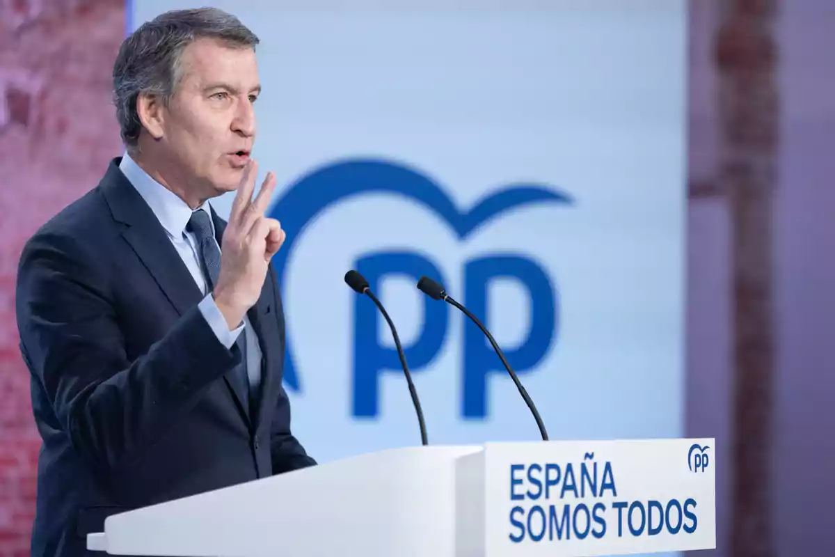 Un hombre en traje hablando en un podio con el logo del PP y el texto 