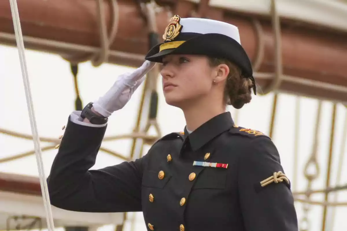 Una persona en uniforme militar realiza un saludo formal a bordo de un barco.