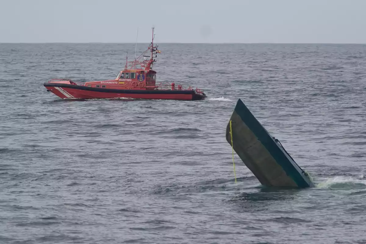 Una embarcación de salvamento marítimo se aproxima a un submarino semihundido en el mar.