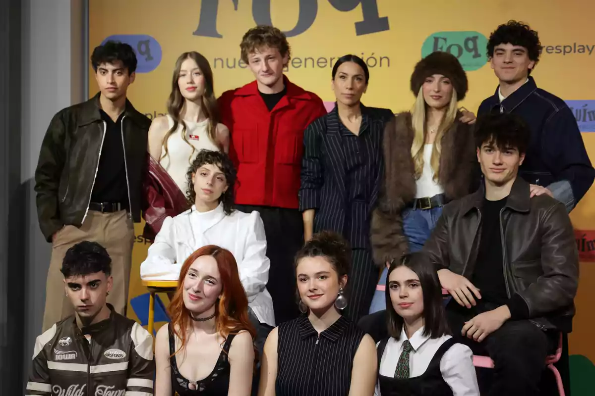 Un grupo de personas posando juntas frente a un fondo amarillo con texto.