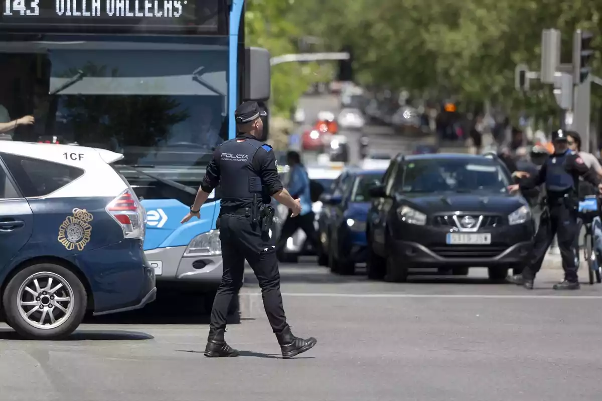 Un policía dirigiendo el tráfico en una calle concurrida con un autobús y varios coches alrededor.