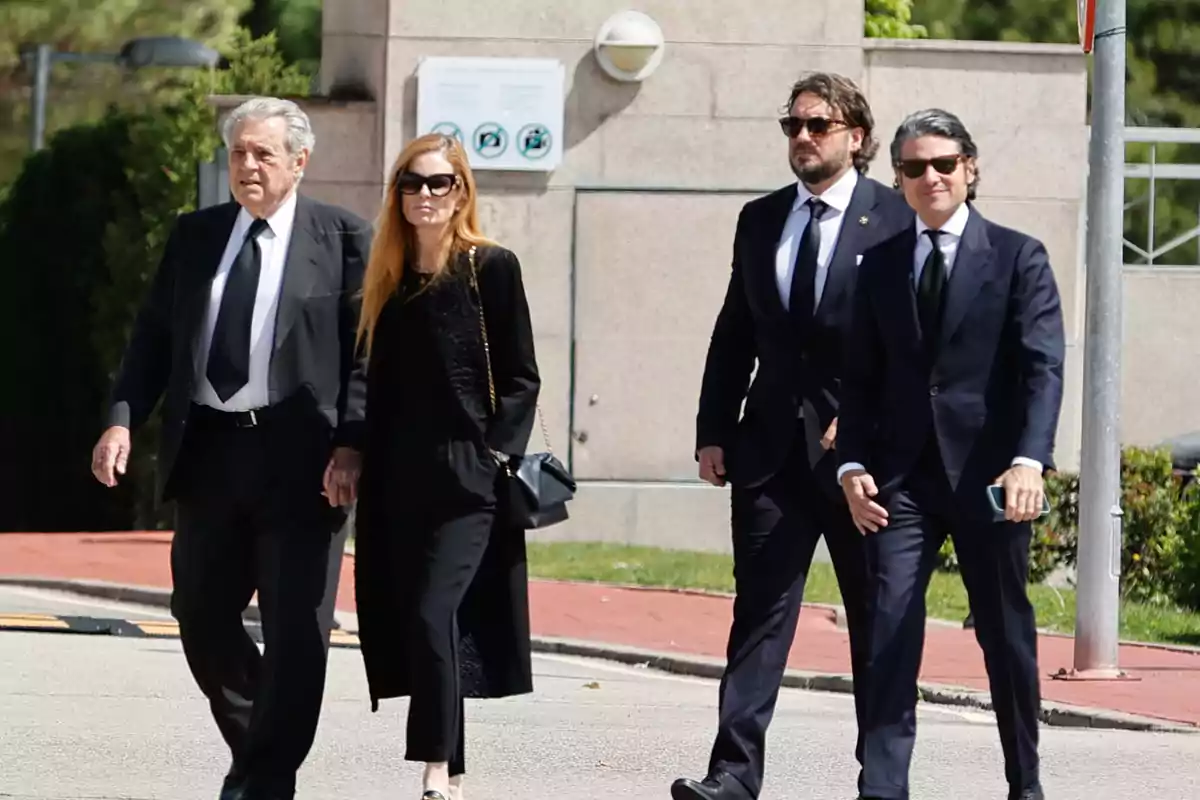 Un grupo de personas vestidas de manera formal camina por una calle en un entorno urbano. Un grupo de personas vestidas de manera formal camina por una calle en un entorno urbano.