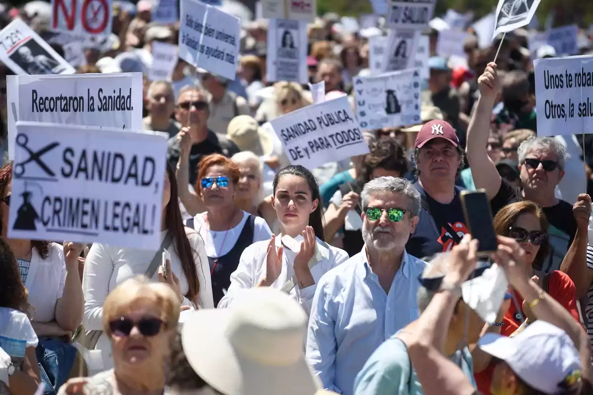 Manifestación multitudinaria en la calle con personas sosteniendo pancartas en defensa de la sanidad pública Manifestación multitudinaria en la calle con personas sosteniendo pancartas en defensa de la sanidad pública