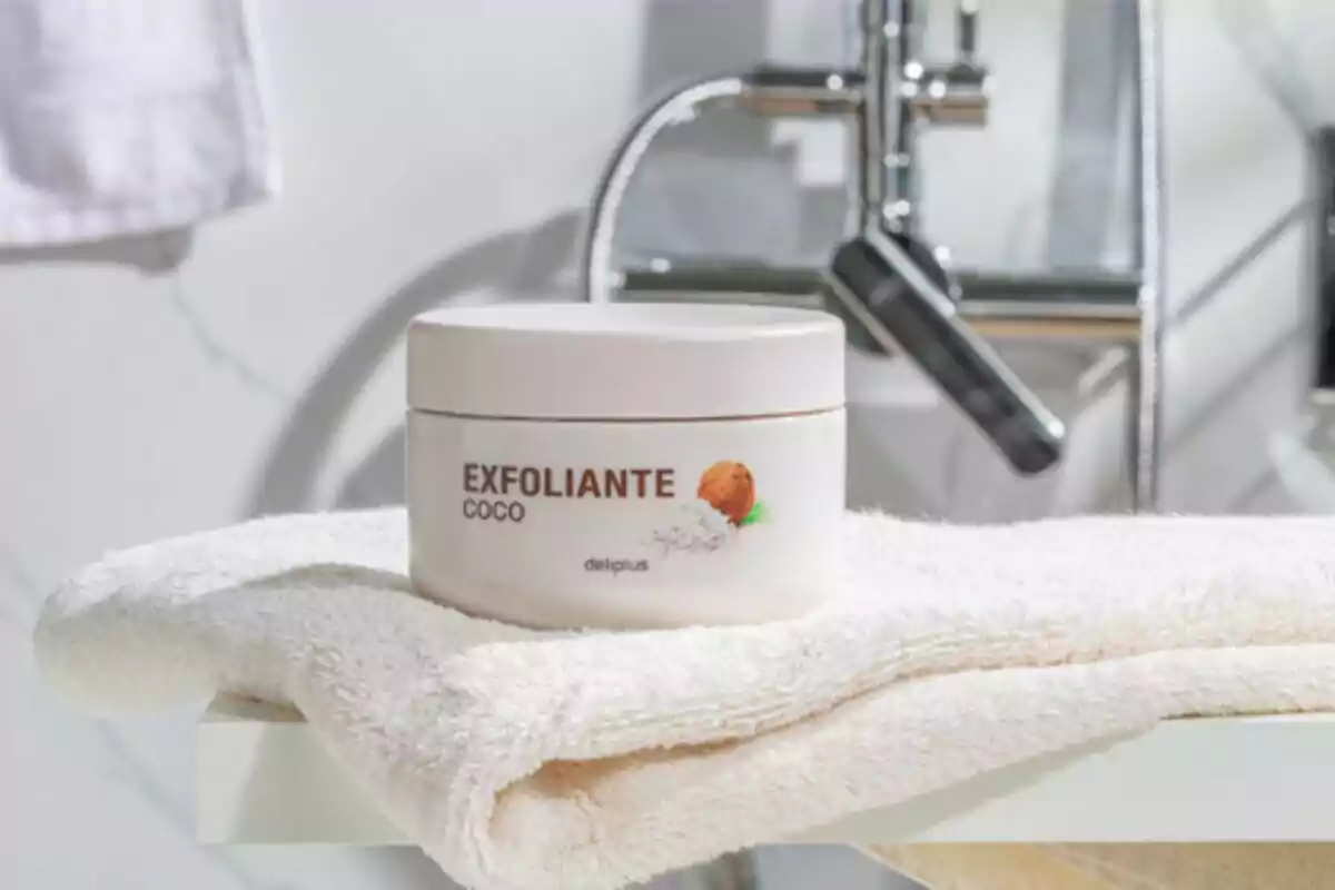 Envase de exfoliante de coco sobre una toalla blanca en un baño. Envase de exfoliante de coco sobre una toalla blanca en un baño.