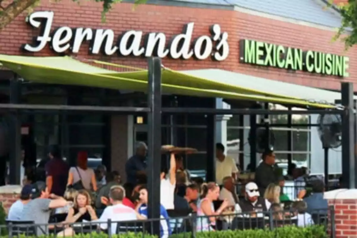 Un restaurante con terraza al aire libre donde varias personas están sentadas disfrutando de una comida. Un restaurante con terraza al aire libre donde varias personas están sentadas disfrutando de una comida.