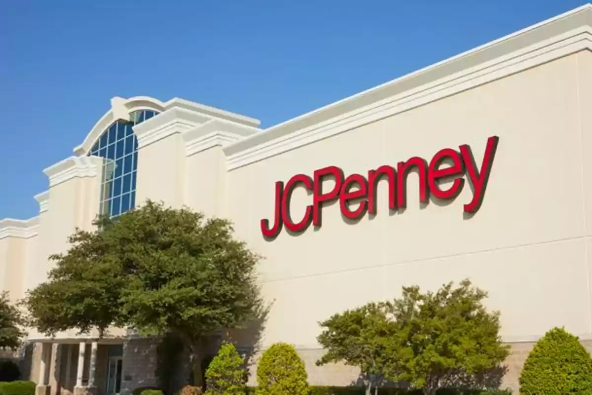 Fachada de una tienda con el logo de JCPenney en letras rojas y árboles en el frente. Fachada de una tienda con el logo de JCPenney en letras rojas y árboles en el frente.