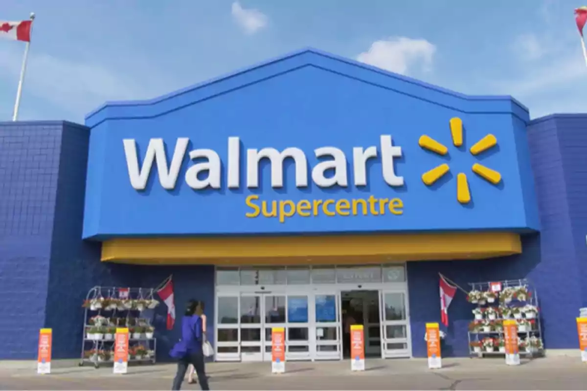 Fachada de un supermercado Walmart Supercentre con una persona caminando hacia la entrada. Fachada de un supermercado Walmart Supercentre con una persona caminando hacia la entrada.