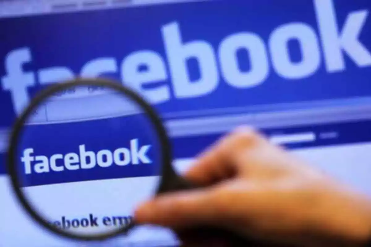 Una lupa enfocando el logotipo de Facebook en una pantalla.
