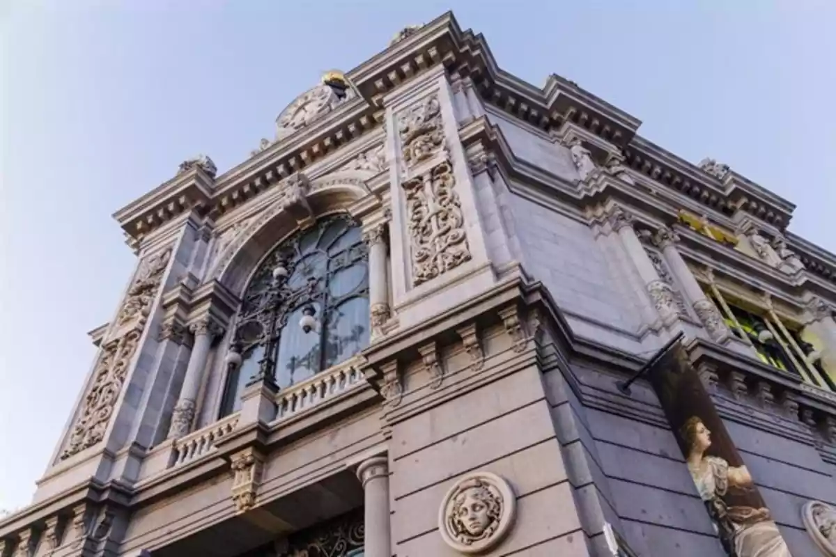 Fachada de un edificio histórico con detalles arquitectónicos ornamentados y un reloj en la parte superior.