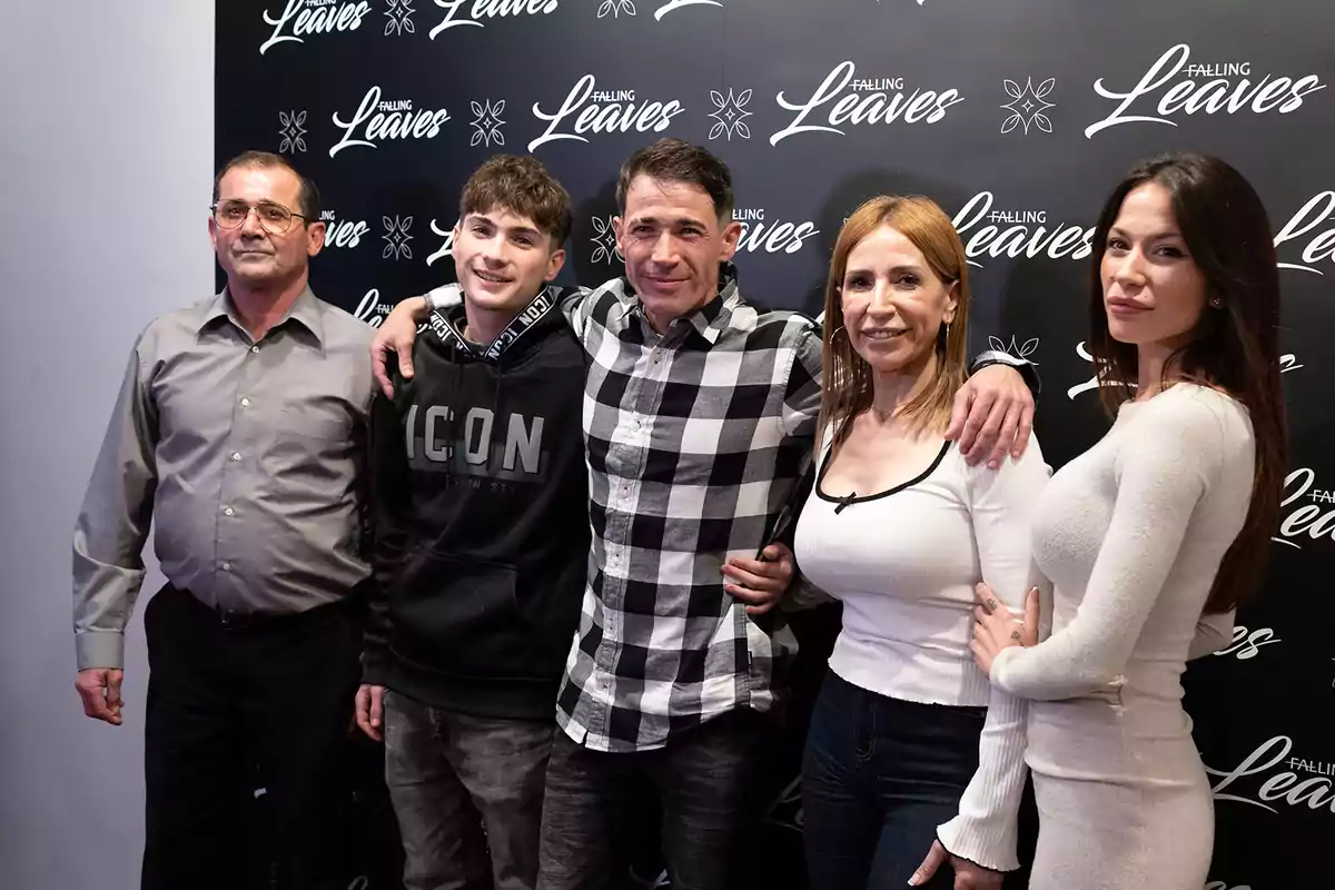 Un grupo de cinco personas posando juntas frente a un fondo con el logo de 