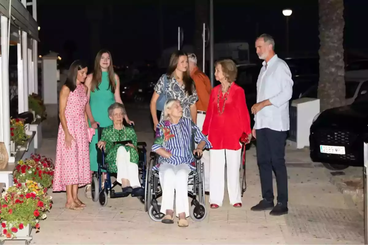 Un grupo de personas, algunas en sillas de ruedas, posando al aire libre por la noche.