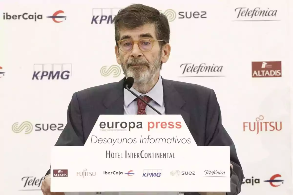 Hombre de cabello y barba canosos con gafas hablando en un atril durante un evento de Europa Press en el Hotel InterContinental
