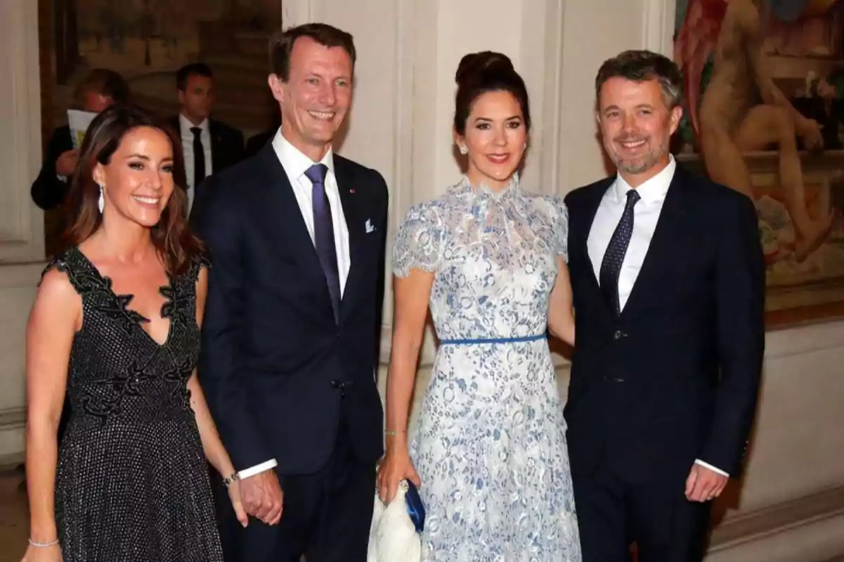 Cuatro personas elegantemente vestidas posan para una foto en un evento formal, dos hombres y dos mujeres sonríen mientras están de pie uno al lado del otro.