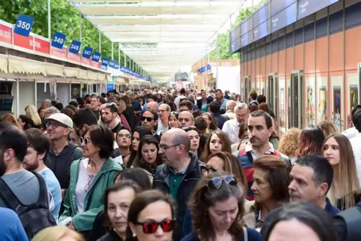 Multitud de personas caminando entre puestos en una feria al aire libre Multitud de personas caminando entre puestos en una feria al aire libre