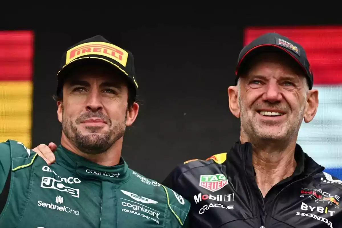 Fernando Alonso y Adrian Newey posan juntos, uno con uniforme verde de Aston Martin y el otro con uniforme negro de Red Bull Racing.