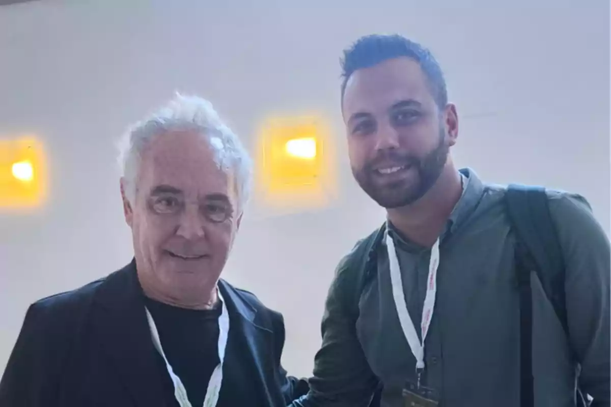 Dos personas posando juntas en un evento con credenciales colgadas al cuello.