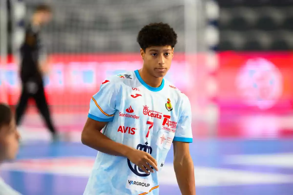 Joven jugador de balonmano con camiseta celeste y el número 7 en una cancha deportiva