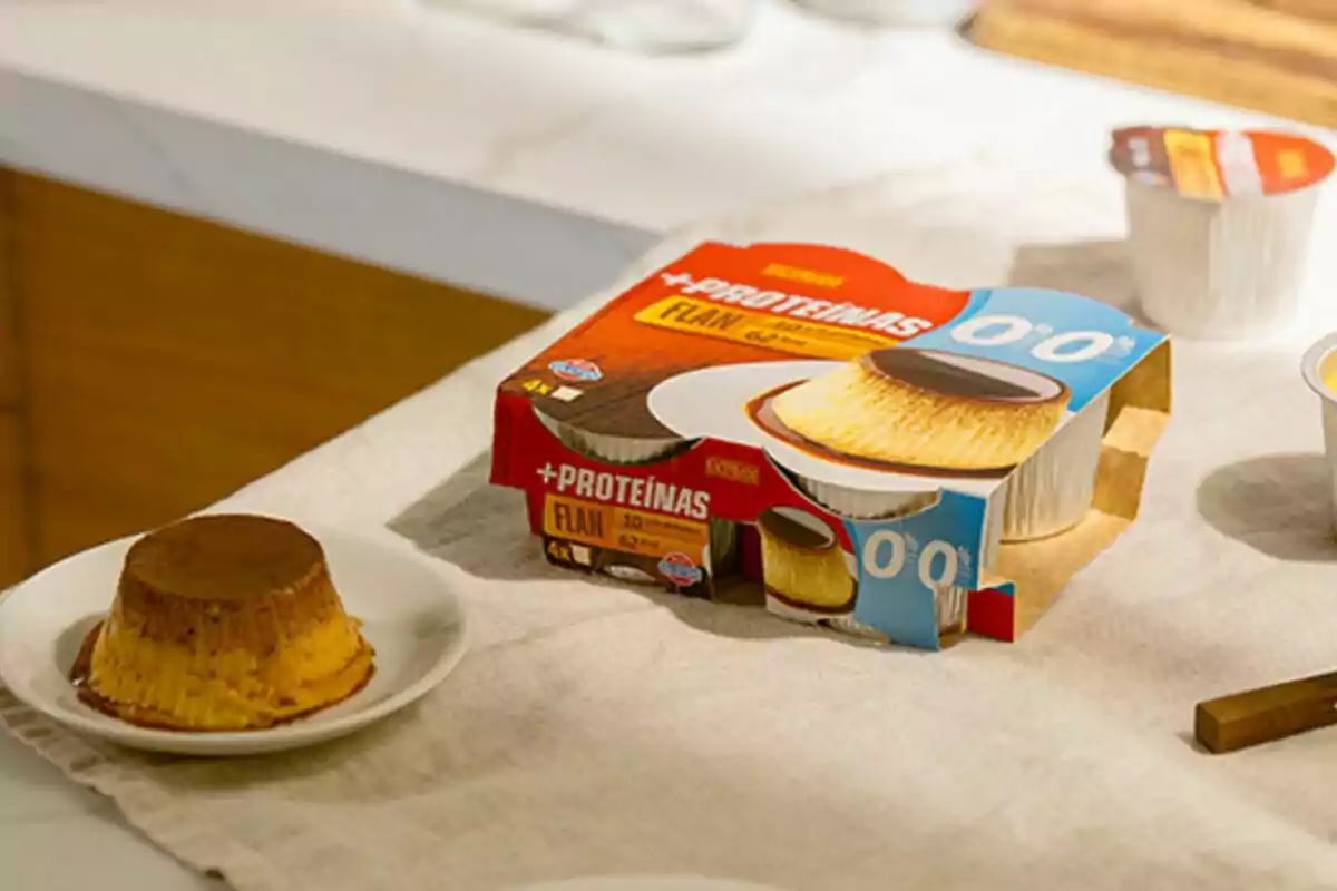Envase de flan de proteínas junto a un flan servido en un plato sobre una mesa. Envase de flan de proteínas junto a un flan servido en un plato sobre una mesa.