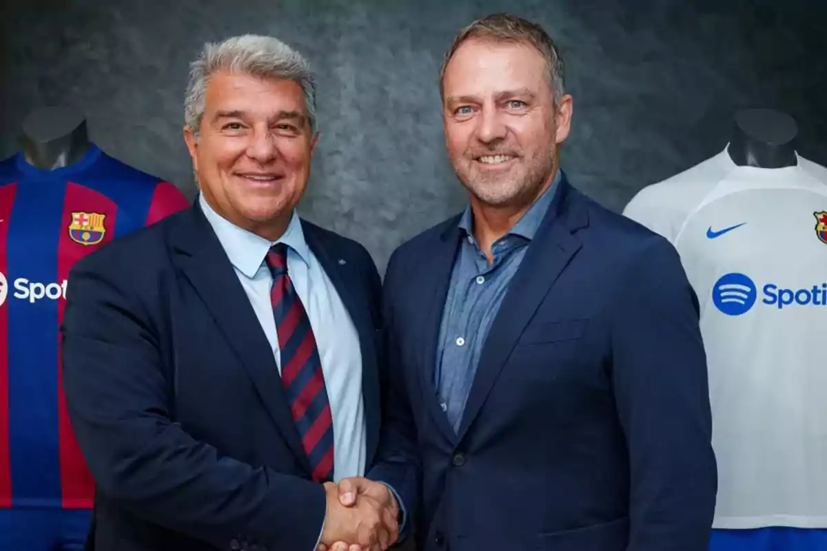 Dos hombres de traje se dan la mano frente a camisetas del FC Barcelona.