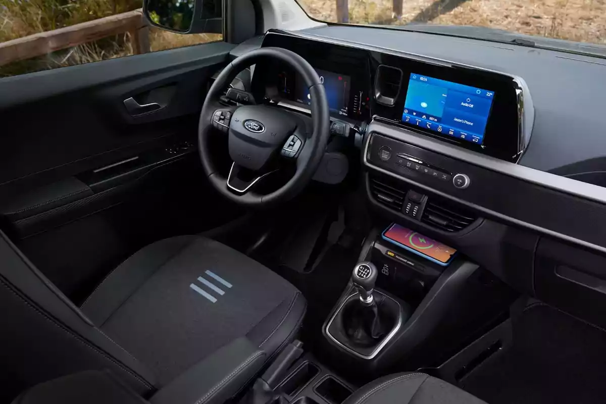 Interior de un automóvil moderno con volante, pantalla táctil y palanca de cambios manual. Interior de un automóvil moderno con volante, pantalla táctil y palanca de cambios manual.