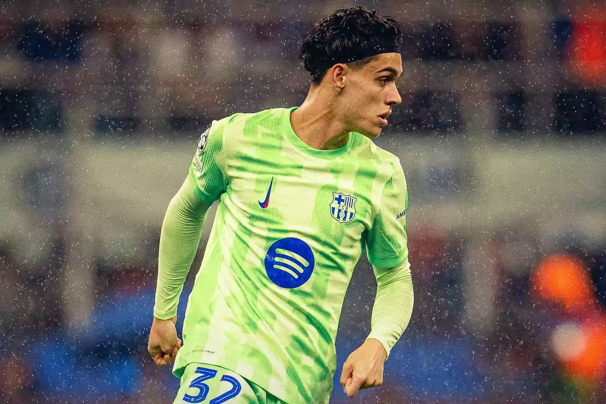 Futbolista con uniforme verde claro del FC Barcelona en medio de un partido bajo la lluvia Futbolista con uniforme verde claro del FC Barcelona en medio de un partido bajo la lluvia