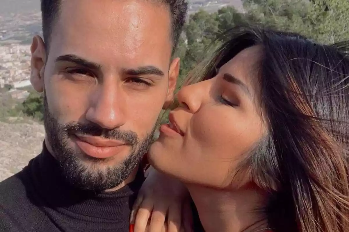 Selfie de Asraf Beno mirando a cámara mientras Isa Pantoja le da un beso en la mejilla Selfie de Asraf Beno mirando a cámara mientras Isa Pantoja le da un beso en la mejilla