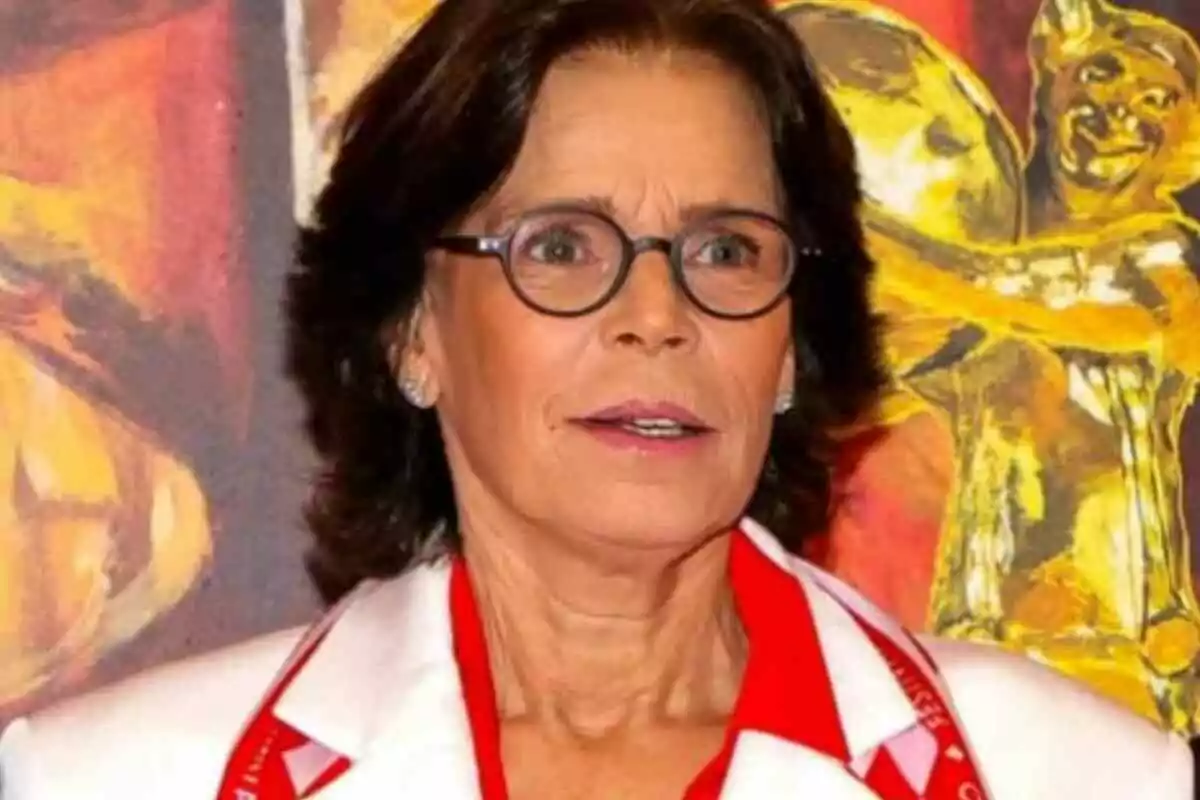 Estefanía de Mónaco con gafas y cabello oscuro lleva una chaqueta blanca y roja frente a un fondo colorido. Estefanía de Mónaco con gafas y cabello oscuro lleva una chaqueta blanca y roja frente a un fondo colorido.