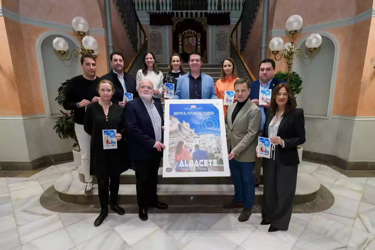 Un grupo de personas posando en un edificio con un cartel promocional de turismo de Albacete.