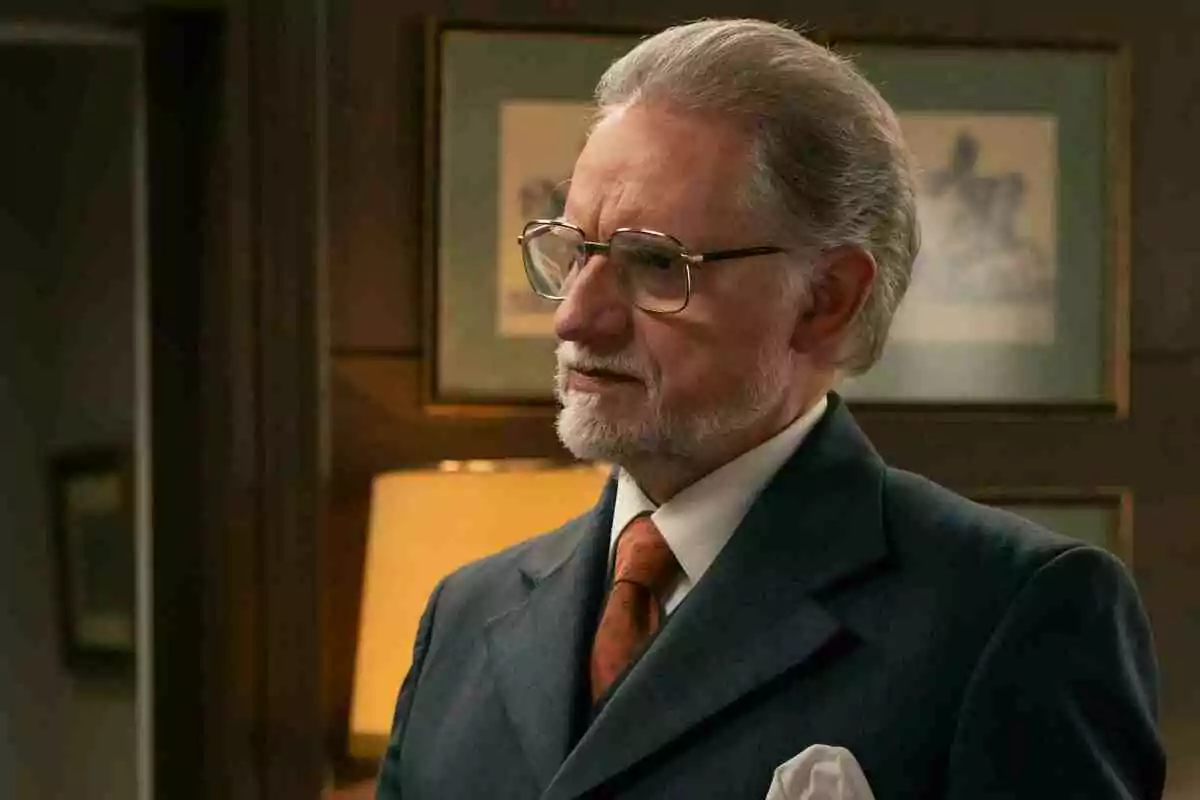 Damián (Nancho Novo) de cabello canoso y barba corta usando gafas y un traje formal con corbata naranja en una oficina elegante Damián (Nancho Novo) de cabello canoso y barba corta usando gafas y un traje formal con corbata naranja en una oficina elegante